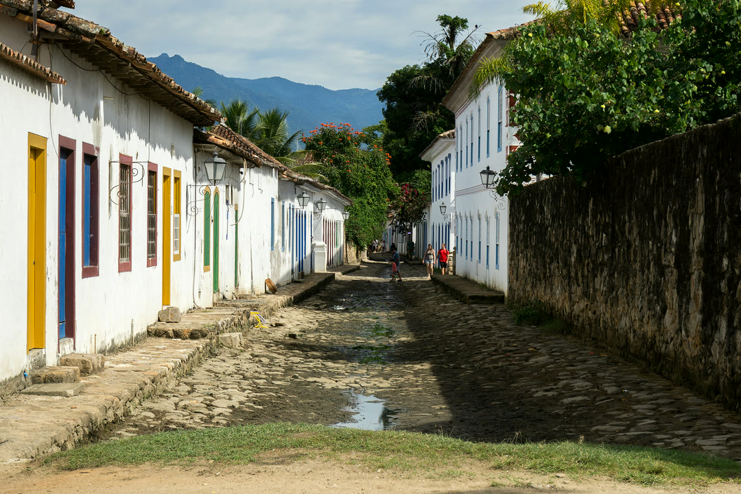 Casarões brancos de portas coloridas no Centro Histórico de Paraty, com a serra ao fundo